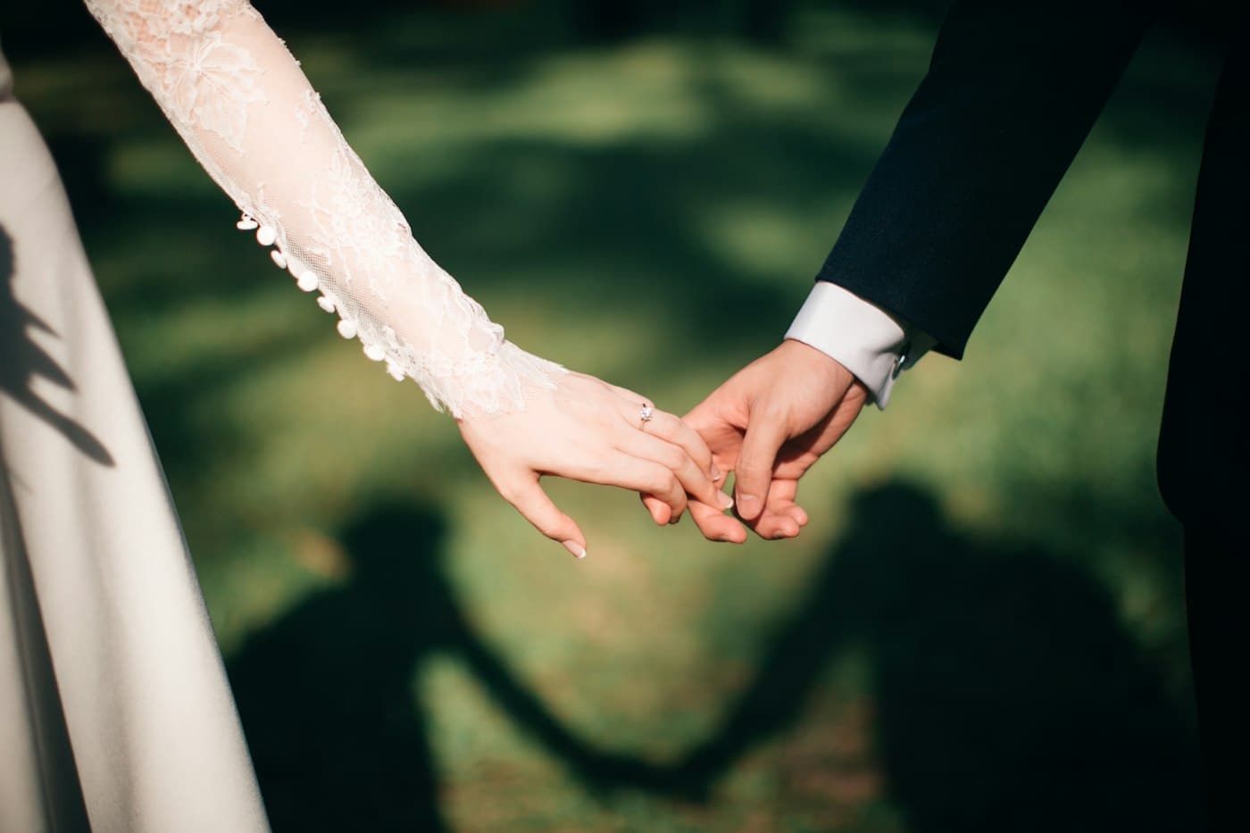 Two hands held up to the sun, one of them wearing a ring.