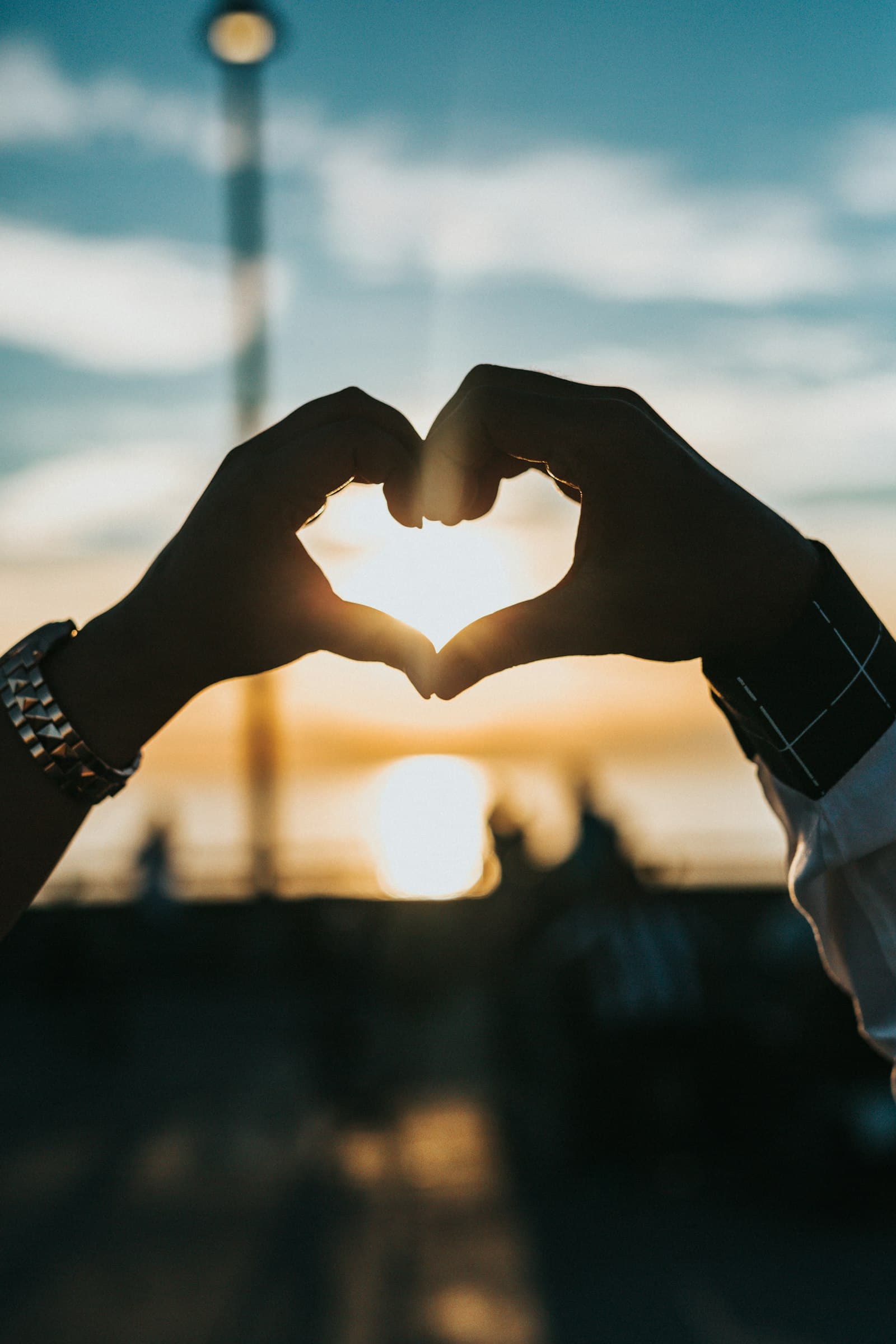 Two hands form a heart against the sun, late in the afternoon.