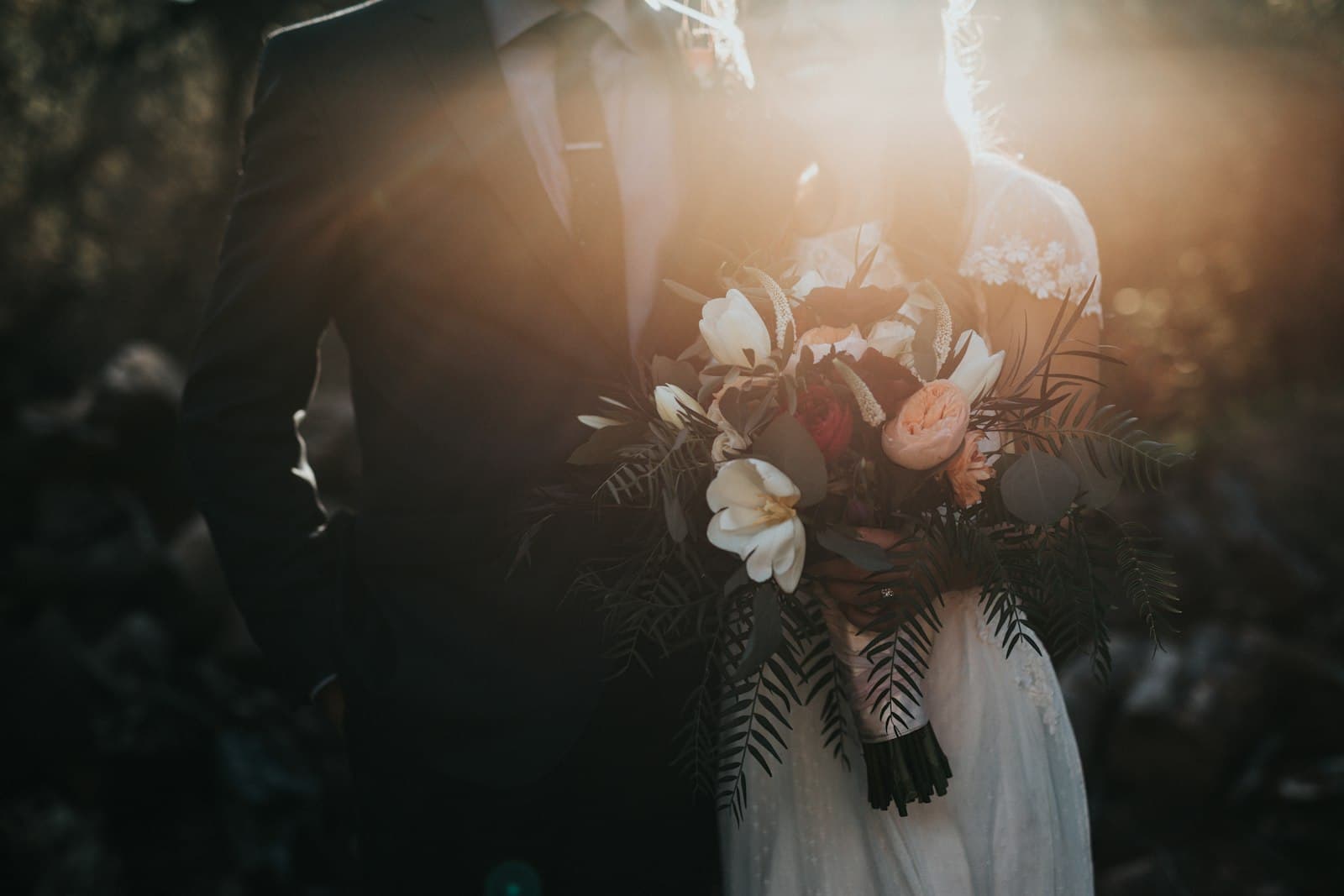 A couple in backlight, she holds a bouquet, the light coming in from the side.